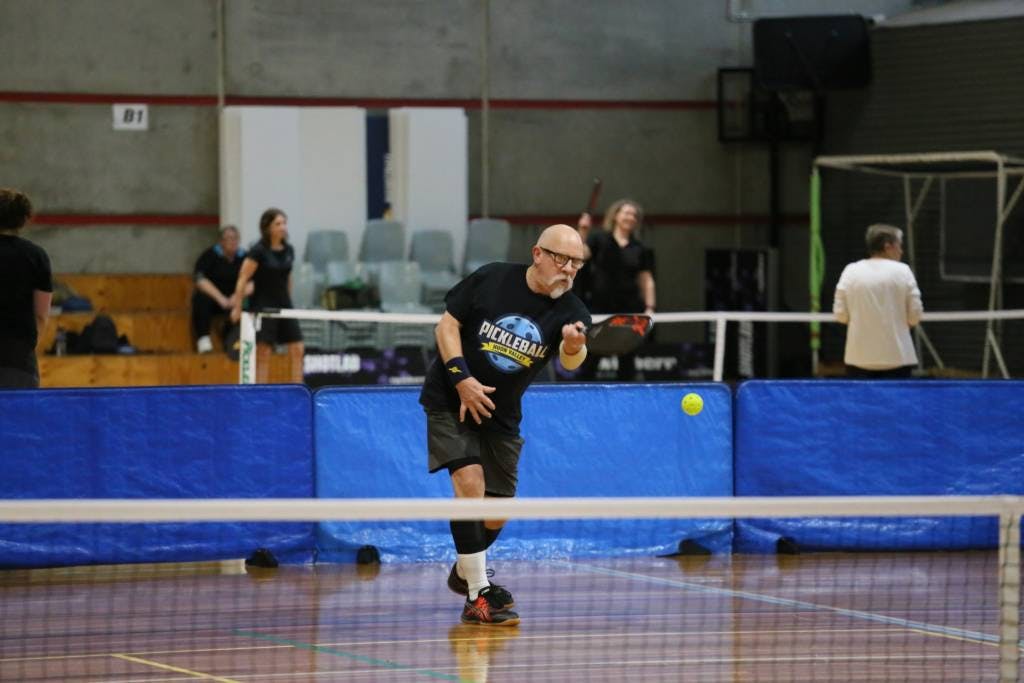 man coming up to net playing pickleball